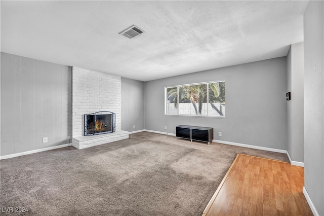 unfurnished living room featuring a brick fireplace and hardwood / wood-style floors