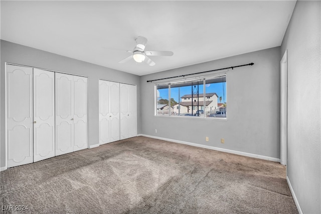 unfurnished bedroom featuring ceiling fan, multiple closets, and carpet floors