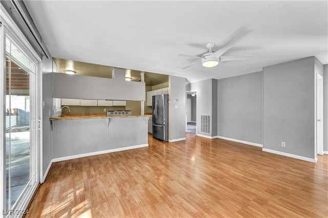 unfurnished living room with light hardwood / wood-style floors, ceiling fan, and sink