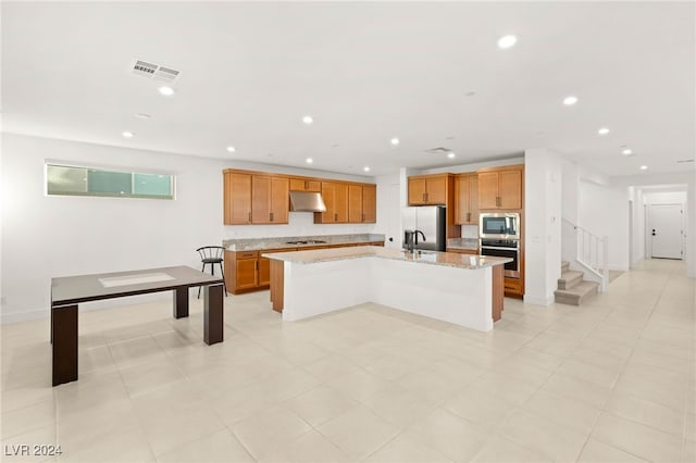 kitchen featuring stainless steel appliances, light tile patterned floors, light stone countertops, sink, and an island with sink