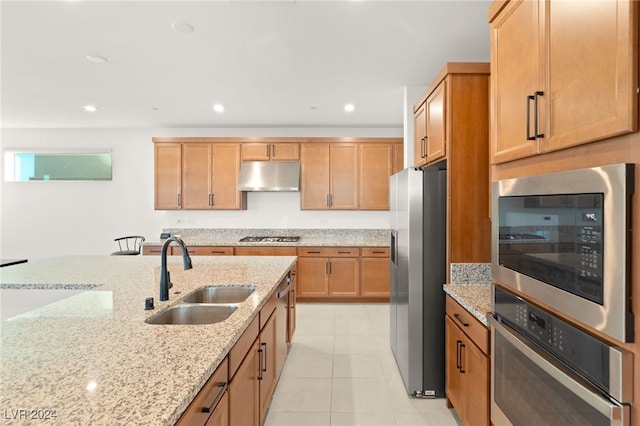 kitchen featuring stainless steel appliances, light tile patterned floors, sink, and light stone counters