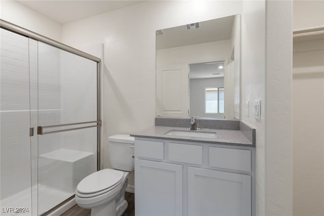 bathroom with vanity, hardwood / wood-style flooring, toilet, and a shower with shower door