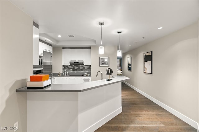 kitchen featuring white cabinetry, a peninsula, decorative backsplash, baseboards, and dark wood-style flooring