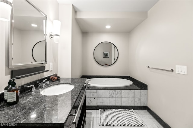 full bathroom with vanity, tiled bath, baseboards, and tile patterned flooring