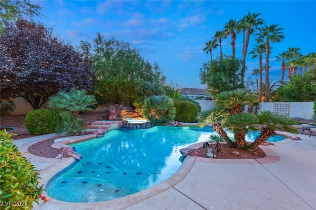 pool at dusk featuring a patio area