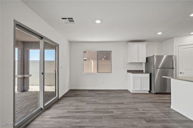 kitchen featuring white cabinets, stainless steel refrigerator, and light wood-type flooring