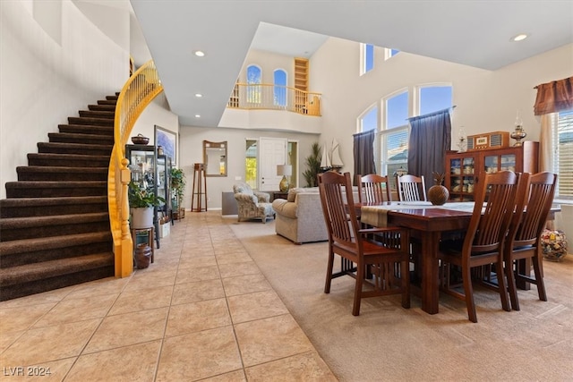 carpeted dining space featuring a wealth of natural light and a high ceiling