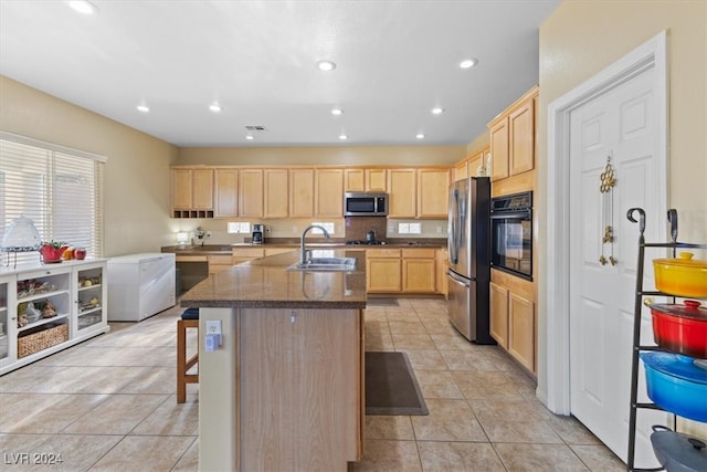 kitchen with a center island with sink, a kitchen breakfast bar, sink, light brown cabinetry, and appliances with stainless steel finishes