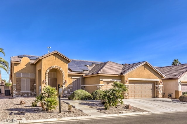 ranch-style house featuring solar panels, a garage, and central AC unit