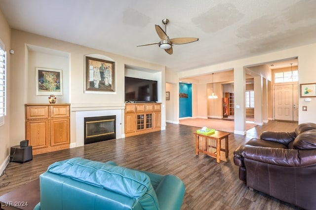 living room with ceiling fan with notable chandelier and dark hardwood / wood-style floors