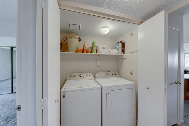 clothes washing area featuring washing machine and dryer, a textured ceiling, and light carpet