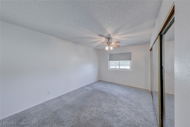 unfurnished bedroom with a closet, a textured ceiling, ceiling fan, and carpet floors