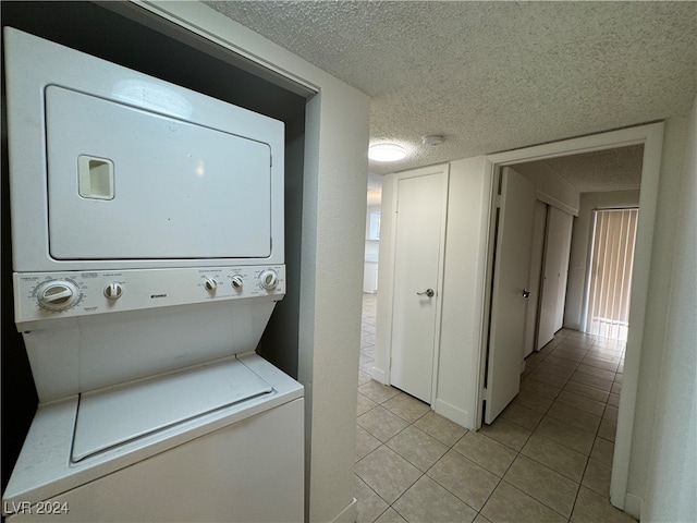 washroom with light tile patterned floors, a textured ceiling, and stacked washer / dryer