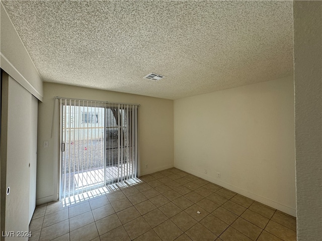 empty room with light tile patterned flooring and a textured ceiling