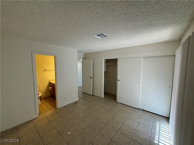 4464 W Desert Inn Rd Unit A, Las Vegas, NV 89102 - unfurnished bedroom featuring a closet, tile patterned flooring, a textured ceiling, and connected bathroom