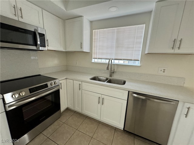 kitchen with light tile patterned floors, white cabinetry, sink, and appliances with stainless steel finishes