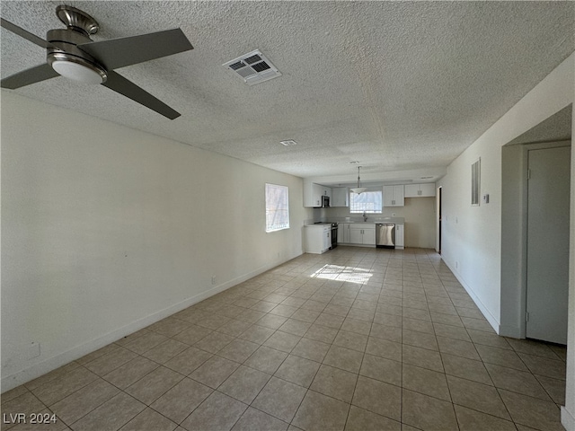 interior space with light tile patterned flooring, ceiling fan, and a textured ceiling