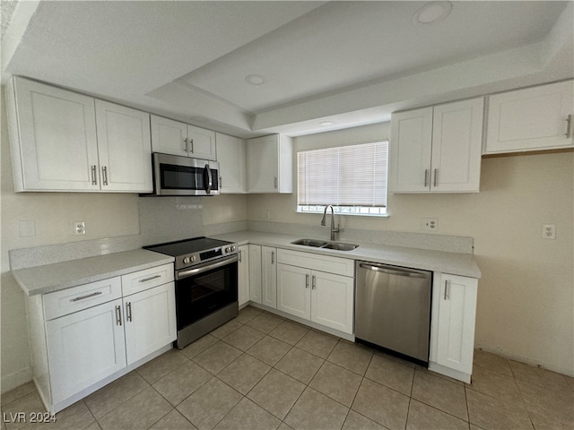 kitchen with stainless steel appliances, light tile patterned flooring, white cabinets, and sink