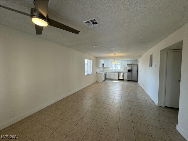 4464 W Desert Inn Rd Unit A, Las Vegas, NV 89102 - unfurnished living room with a textured ceiling, baseboards, light tile patterned flooring, ceiling fan, and a sink