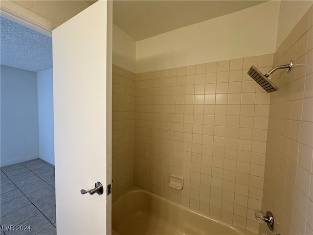 bathroom with tile patterned flooring, tiled shower / bath, and a textured ceiling