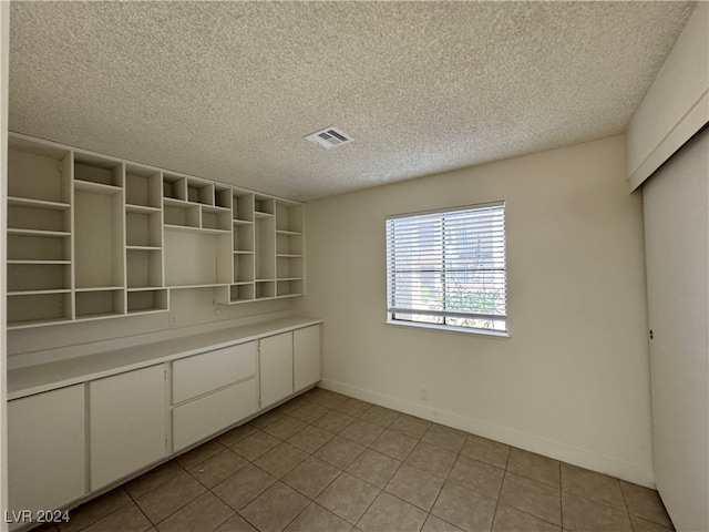 interior space featuring a textured ceiling and light tile patterned floors