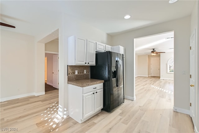 kitchen with white cabinetry, black fridge with ice dispenser, light hardwood / wood-style floors, and tasteful backsplash