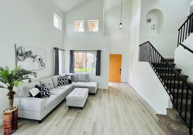 living room with a wealth of natural light, light wood-type flooring, and high vaulted ceiling