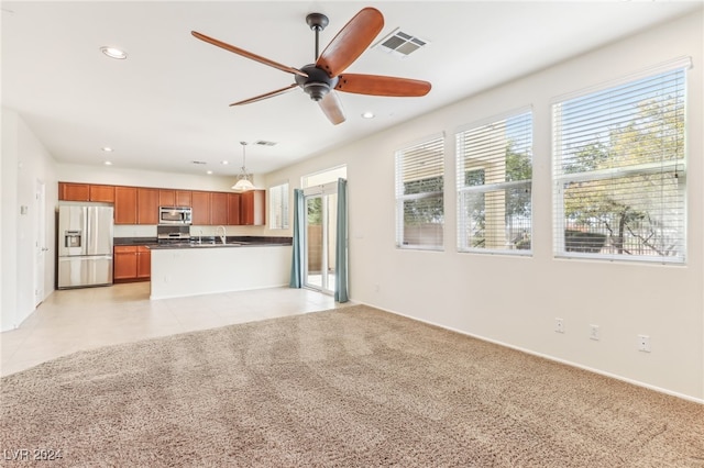 unfurnished living room featuring light colored carpet, ceiling fan, and a healthy amount of sunlight