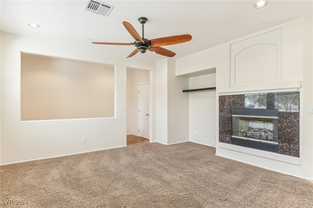 unfurnished living room featuring carpet flooring, a tile fireplace, and ceiling fan