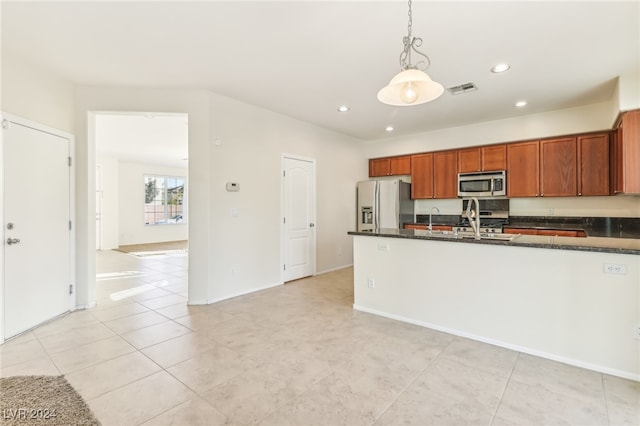 kitchen featuring light tile patterned flooring, appliances with stainless steel finishes, hanging light fixtures, and dark stone countertops