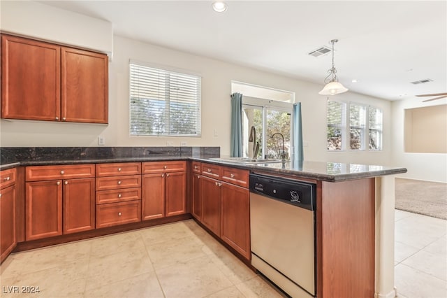 kitchen featuring pendant lighting, stainless steel dishwasher, dark stone counters, and sink