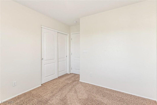 unfurnished bedroom with light carpet and a closet