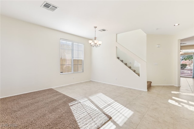 spare room featuring a chandelier, light tile patterned floors, and a healthy amount of sunlight