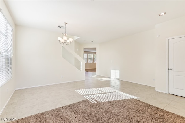 tiled empty room featuring a notable chandelier