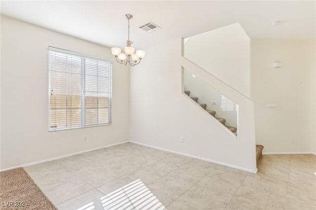 tiled empty room with a chandelier