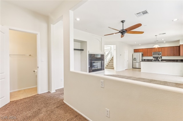 kitchen featuring ceiling fan, a fireplace, light colored carpet, and stainless steel appliances