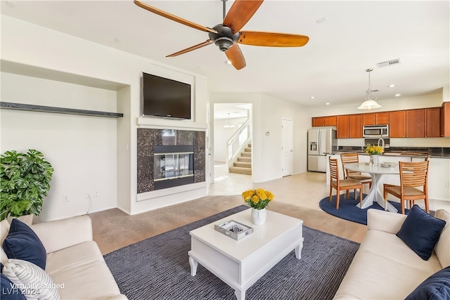 living room with ceiling fan, a high end fireplace, and light hardwood / wood-style flooring