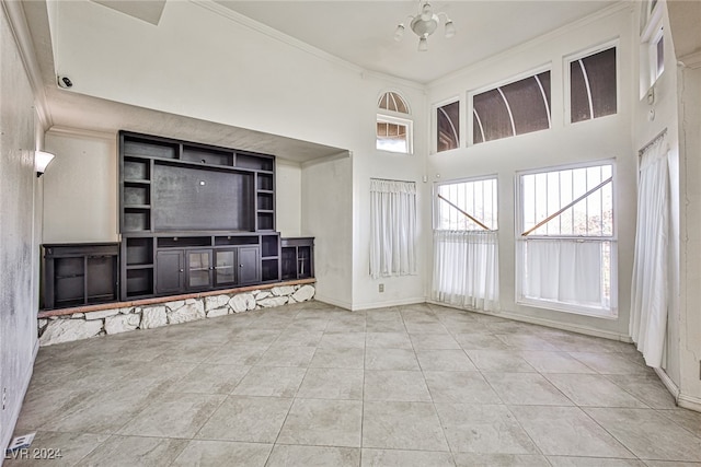 unfurnished living room with a high ceiling, light tile patterned floors, and ornamental molding