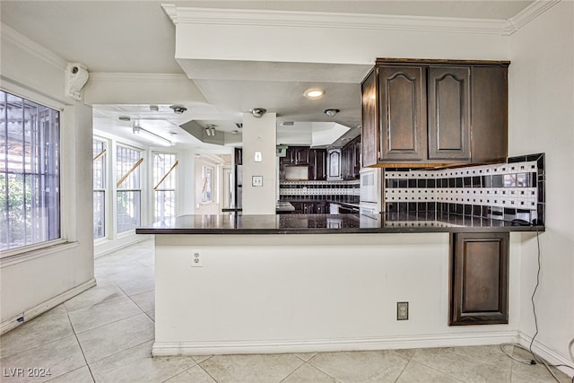 kitchen featuring ornamental molding, kitchen peninsula, and dark brown cabinetry