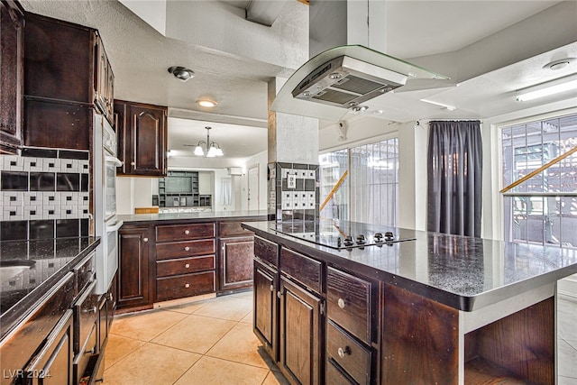 kitchen with black electric cooktop, dark brown cabinetry, a healthy amount of sunlight, and a center island