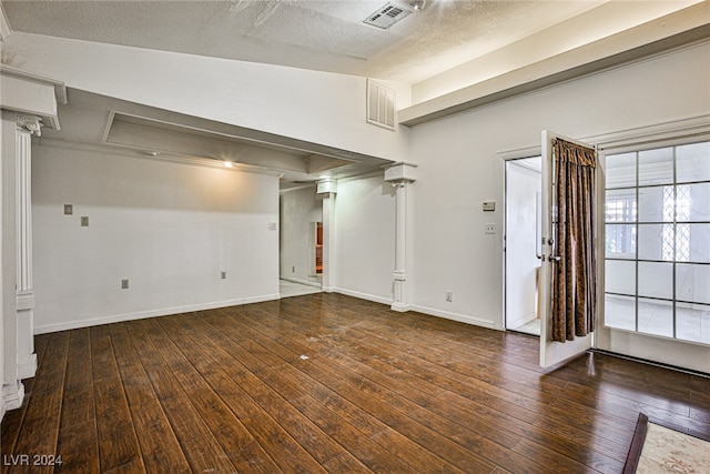 interior space featuring dark hardwood / wood-style flooring, a textured ceiling, and ornate columns