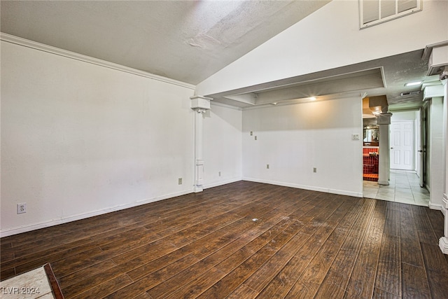 unfurnished room featuring dark wood-type flooring, a textured ceiling, and vaulted ceiling