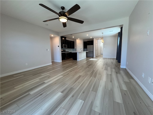 unfurnished living room with sink, ceiling fan, and light hardwood / wood-style flooring