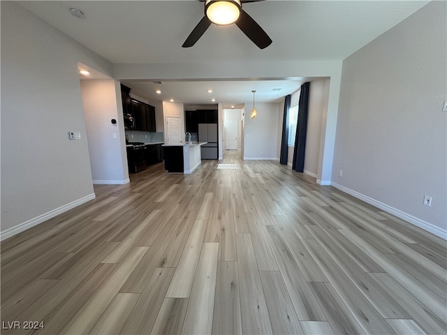 unfurnished living room with light hardwood / wood-style flooring, ceiling fan, and sink