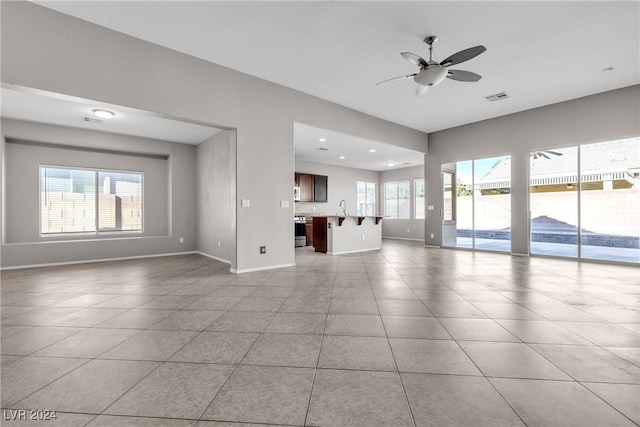 unfurnished living room featuring ceiling fan, a healthy amount of sunlight, light tile patterned floors, and sink