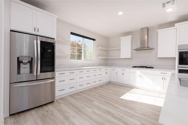 kitchen featuring stainless steel appliances, visible vents, wall chimney range hood, light wood-type flooring, and open shelves