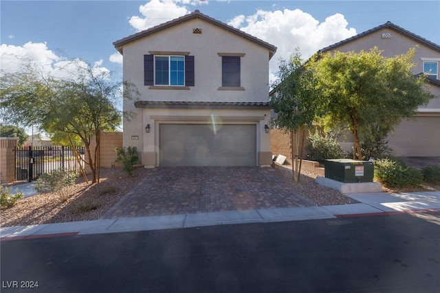 traditional-style home featuring a garage, fence, decorative driveway, and stucco siding