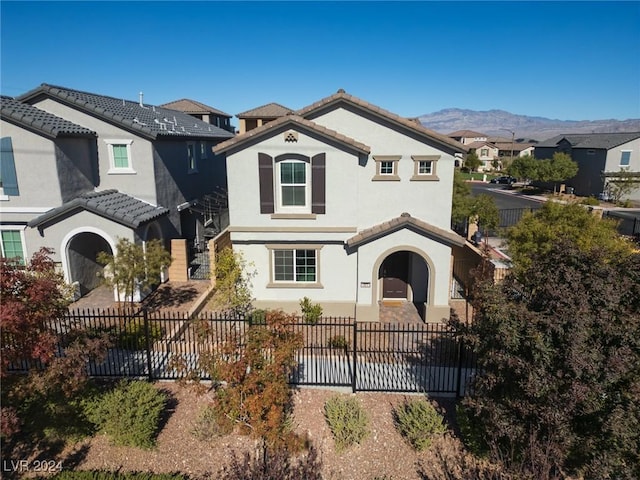 mediterranean / spanish-style home featuring a tile roof, fence, a mountain view, and stucco siding