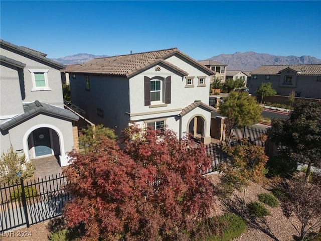 view of front of property featuring stucco siding, fence, a mountain view, and a tiled roof