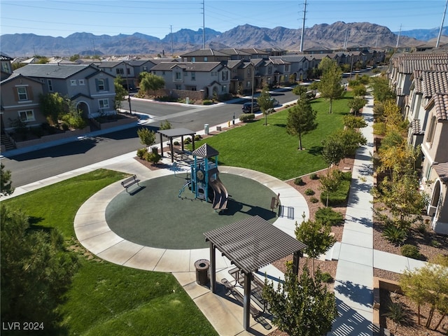 view of community with a mountain view, playground community, a yard, and a residential view